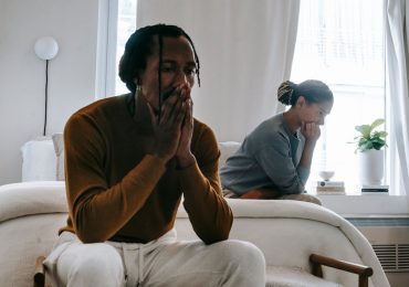 Couple sitting on bed after having argument leading to family separation.